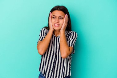 Genç Hintli bir kadın mavi arka planda yalnız başına sızlanıyor ve ağlıyor..