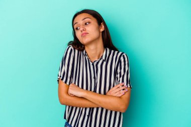 Mavi arka planda izole edilmiş genç Hintli kadın tekrarlanan bir görevden yoruldu.