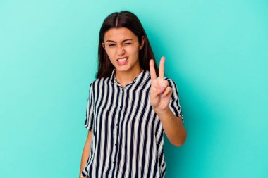 Mavi arka planda izole edilmiş genç Hintli kadın iki numarayı parmaklarıyla gösteriyor..