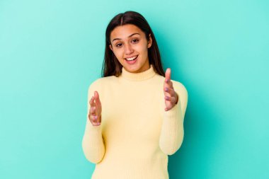 Mavi arka planda izole edilmiş genç Hintli kadın kameraya sarıldığı için kendinden emin hissediyor..