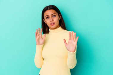 Genç Hintli kadın mavi arka planda izole edildi. Yakın bir tehlike nedeniyle şoka uğruyor.