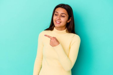 Mavi arka planda soyutlanmış genç bir Hintli kadın gülümsüyor, neşeli ve keyifli görünüyor..