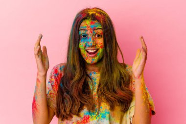 Kutsal bayramı kutlayan genç Hintli kadın beyaz arka planda izole edilmiş hoş bir sürprizle karşılanıyor, heyecanlı ve el kaldırıyor..