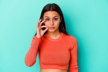 Mavi arka planda izole edilmiş genç Hintli kadın parmakları dudaklarında bir sır saklıyor..