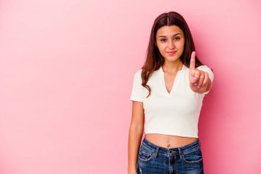 Pembe arka planda izole edilmiş genç Hintli kadın bir numarayı parmağıyla gösteriyor..