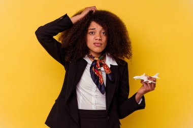 Sarı arka planda izole edilmiş küçük bir uçak tutan genç Afrikalı Amerikalı hostes şok olmuştu..