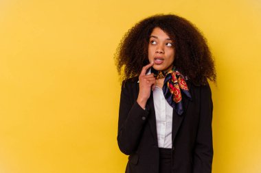 Genç Afrikalı Amerikalı hostes sarı arka planda izole edilmiş şüpheli ve şüpheci bir ifadeyle yana bakıyor..