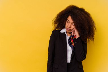 Genç Afrikalı Amerikalı hostes, sarı arka planda izole edilmiş, üzgün ve düşünceli, fotokopi alanına bakıyor..