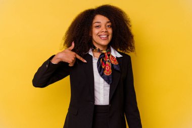 Genç Afrikalı Amerikalı hostes, sarı arka planda izole edilmiş. Elle bir tişört fotokopi alanını işaret ediyor.