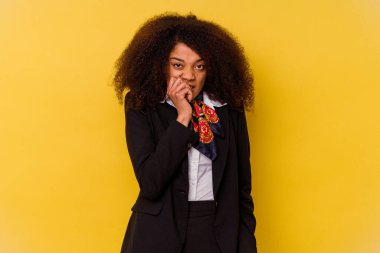 Genç Afrikalı Amerikalı hostes sarı arka planda izole edilmiş tırnak yiyor, gergin ve çok endişeli..