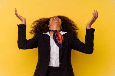 Genç Afrikalı Amerikalı hostes sarı arka planda izole edilmiş gökyüzüne haykırıyor, yukarı bakıyor, hayal kırıklığına uğramış.