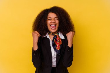 Genç Afrikalı Amerikalı hostes sarı arka planda izole edilmiş tasasız ve heyecanlı bir şekilde tezahürat yapıyor. Zafer konsepti.