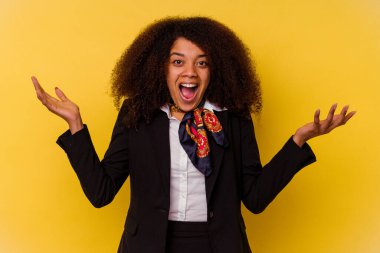 Genç Afrikalı Amerikalı hostes sarı arka planda izole edilmiş hoş bir sürprizle karşılaşıyor, heyecanlı ve el kaldırıyor..