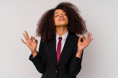 Beyaz arka planda izole edilmiş takım elbiseli genç Afrikalı Amerikalı iş kadını sıkı çalışma gününden sonra dinleniyor, yoga yapıyor..