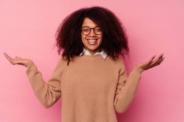 Genç Afrikalı Amerikalı bir kadın pembe arka planda izole edilmiş hoş bir ifade sergiliyor..