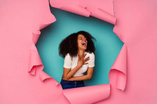 若いアフリカ系アメリカ人の女性が青い背景に孤立紙で喜んで笑うと胃の上に手を保つことが楽しい — ストック写真