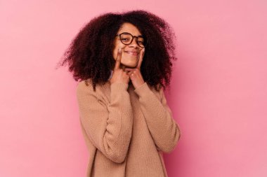 Genç Afrikalı Amerikalı kadın pembe arka planda izole edilmiş iki seçenek arasında şüphe duyuyor..