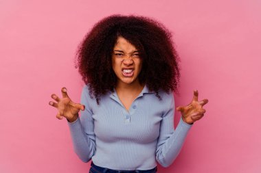 Pembe arka planda izole edilmiş genç Afro-Amerikalı kadın pençelerini kedi taklidi yaparken gösteriyor, agresif bir hareket..