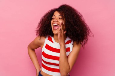 Genç Afrikalı Amerikalı bir kadın pembe arka planda izole edilmiş ve heyecanlı bir şekilde bağırıyor..
