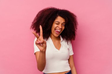 Genç Afrikalı Amerikalı kadın pembe arka planda izole edilmiş. İki numarayı parmaklarıyla gösteriyor..