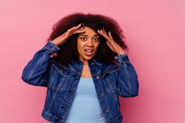 Genç Afrikalı Amerikalı kadın pembe arka planda izole edilmiş. Hoş bir sürpriz alıyor, heyecanlı ve el kaldırıyor..