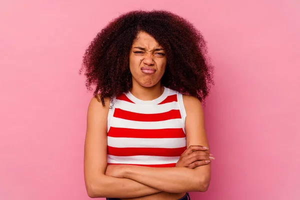 Young african american woman isolated on pink background blows cheeks, has tired expression. Facial expression concept.