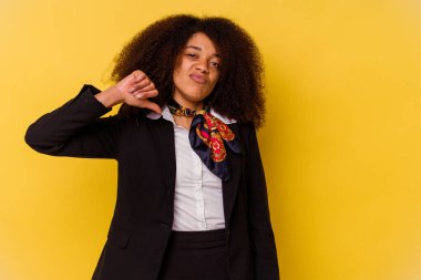 Genç Afrikalı Amerikalı hostes sarı arka planda izole edilmiş, hoşlanmadığı bir jest gösteriyor, başparmakları aşağıda. Anlaşmazlık konsepti.