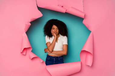 Mavi arka planda izole edilmiş yırtık bir kağıda sarılı genç Afrikalı Amerikalı kadın sıkılmış, yorgun ve dinlenmeye ihtiyacı var..