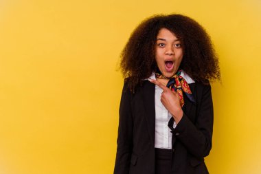 Sarı arka planda izole edilmiş genç Afrikalı Amerikalı hostes yan tarafı gösteriyor.