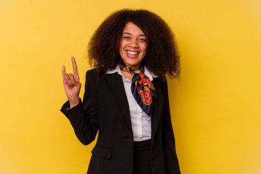 Genç Afrikalı Amerikalı hostes sarı arka planda izole edilmiş bir şekilde boynuz hareketi bir devrim konsepti olarak gösteriyor..