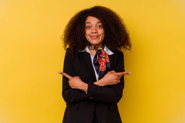 Sarı arka plan noktalarında izole edilmiş genç Afrikalı Amerikalı hostes iki seçenekten birini seçmeye çalışıyor..