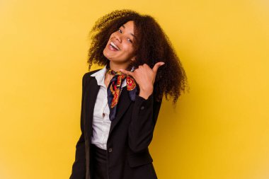 Sarı arka planda izole edilmiş genç Afrikalı Amerikalı hostes parmakları olan bir cep telefonu hareketi gösteriyor..