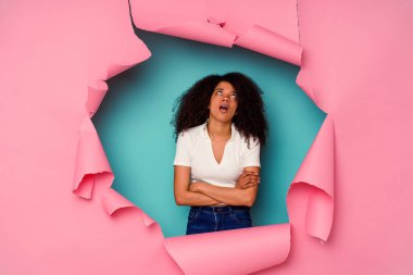 Genç Afrikalı Amerikalı yırtık bir kadın mavi arka planda izole edilmiş. Tekrarlanan bir görevden yorulmuş..