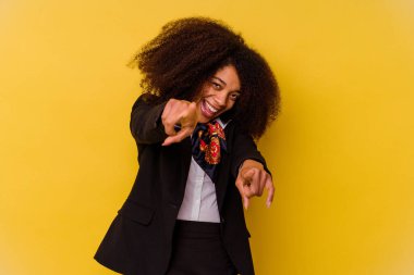 Genç Afrikalı Amerikalı hostes, sarı arka planda izole edilmiş, gülümseyen, ön tarafı işaret eden..