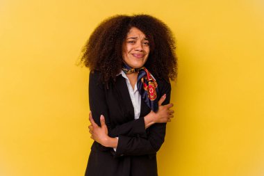 Genç Afrikalı Amerikalı hostes sarı arka planda izole edilmiş. Düşük sıcaklıktan ya da hastalıktan dolayı soğuyor..