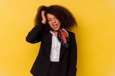 Genç Afrikalı Amerikalı hostes sarı arka planda izole edilmiş yorgun ve uykulu bir şekilde ellerini başının üstünde tutuyor..