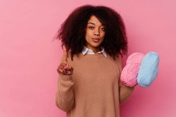 若いですアフリカ系アメリカ人女性を保持しています縫製糸ピンクの背景に隔離された指でナンバーワンを示す — ストック写真