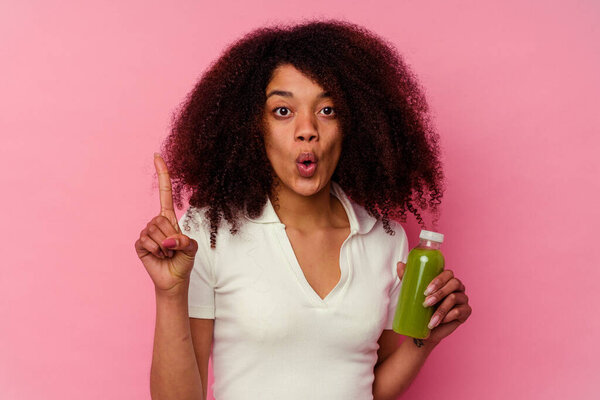 Young african american woman drinking a healthy smoothie isolated on pink background having some great idea, concept of creativity.
