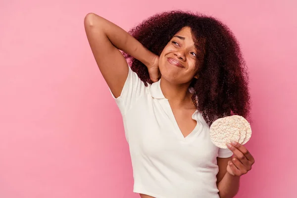 年轻的非洲裔美国女人吃着用粉红背景隔离起来的米糕 头脑清醒地思考着 做出了选择 — 图库照片