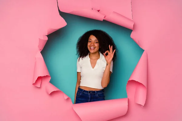 若いですアフリカ系アメリカ人女性で引き裂かれた紙隔離上の青背景陽気で自信を持ってショーOkジェスチャー — ストック写真