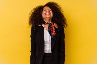 Sarı arka planda izole edilmiş genç Afrikalı Amerikalı hostes gülüyor ve gözlerini kapıyor, rahatlamış ve mutlu hissediyor..