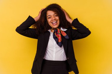 Sarı arka planda izole edilmiş genç Afrikalı Amerikalı hostes ellerini başının üstünde tutarak neşeyle gülüyor. Mutluluk kavramı.