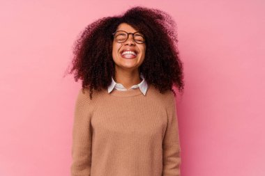 Genç Afro-Amerikalı kadın pembe arka planda izole edilmiş, gülüyor ve gözlerini kapatıyor, rahatlamış ve mutlu hissediyor..