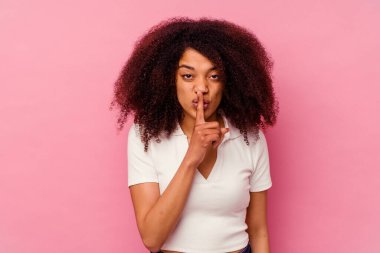 Genç Afrikalı Amerikalı kadın pembe arka planda izole edilmiş bir şekilde sır saklıyor ya da sessizlik istiyor..