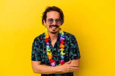 Sarı arka planda izole edilmiş Hawaii kolyesi takan beyaz bir adam gülüyor ve eğleniyor..