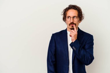 Beyaz arka planda izole edilmiş genç bir iş adamı şüpheli ve şüpheci bir ifadeyle yana bakıyor..