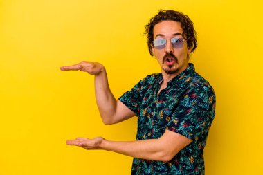 Sarı arka planda izole edilmiş yaz kıyafetleri giyen genç beyaz adam elleri arasında bir fotokopi alanı tutarken şok ve hayrete düştü..