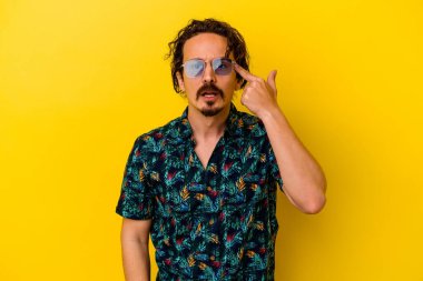 Sarı arka planda izole edilmiş yaz kıyafetleri giyen genç beyaz adam işaret parmağıyla hayal kırıklığı jesti yapıyor..