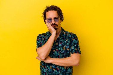 Sarı arka planda izole edilmiş yaz kıyafetleri giyen, sıkılmış, yorgun ve dinlenmeye ihtiyacı olan genç beyaz bir adam..