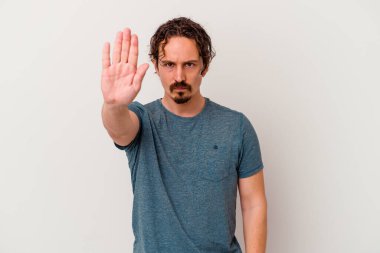 Beyaz arka planda izole edilmiş genç beyaz bir adam elini uzatmış, dur işareti göstererek seni engelliyor..